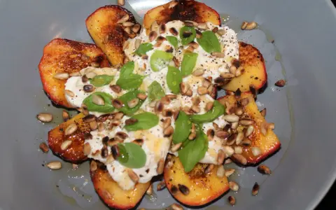 Grillad persika burrata med solrosfrön och basilika. En somrig rätt som smälter i munnen.