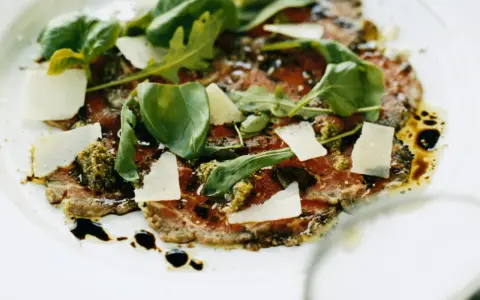En läcker carpaccio med tunt skivad biff, parmesan, ruccola och pesto. Ett perfekt carpaccio recept för en fin middag.