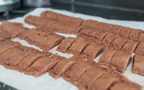 Chokladsnittar recept: Nybakade, mörka chokladkakor uppskurna i bitar på bakplåtspapper.