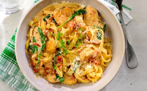En krämig pastarätt med kyckling och soltorkade tomater, toppad med parmesan och färska örter.