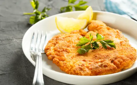 En gyllene schnitzel med citron och persilja, perfekt till ett glas vin.