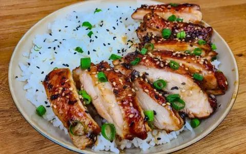 Skivad kyckling i gochujang marinad, serverad med ris och toppad med sesamfrön och salladslök. En härlig rätt som lockar smaklökarna.