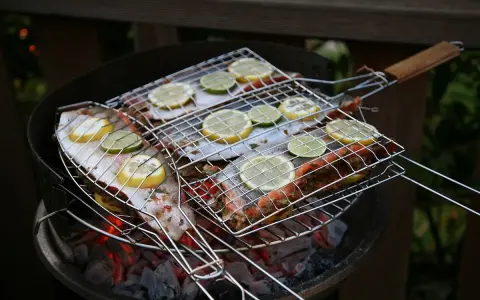 Grillad fisk med citron- och limeskivor på en kolgrill. Doften av sommar och god mat sprider sig.