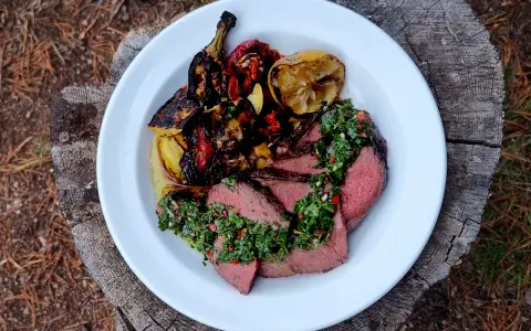 Skivat picanha på en tallrik med grillade grönsaker och citron. Perfekt för en somrig picanha grilla.