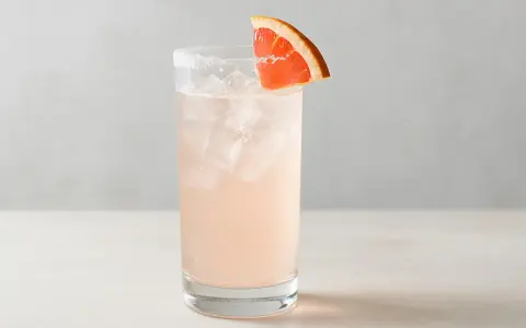 En uppfriskande Paloma drink med is och en grapefruktskiva som garnering.