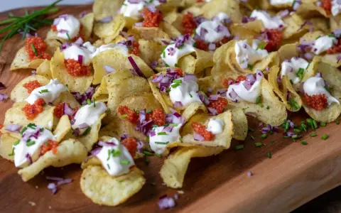 Krispiga chips med klickar av smetana, röd rom, finhackad rödlök och gräslök. En festlig förrätt!