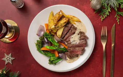 En festlig tallrik med saftig biff, rostade potatisklyftor, grönsaker och en krämig sås. Perfekt glutenfri mat för högtider.