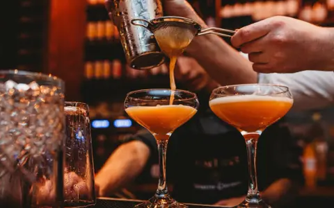 En bartender häller upp en Pornstar Martini i ett elegant glas.
