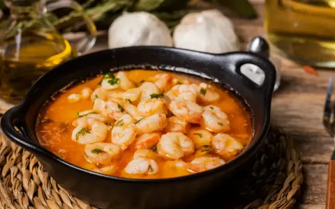 En skål med saftiga gambas pil pil i en het oljeblandning, med vitlök och persilja. En klassisk spansk rätt som värmer själen.
