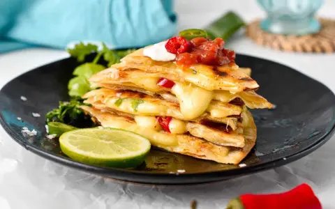 En stapel krispiga quesadillas med smält ost, jalapeños och salsa. Ett perfekt monterey jack ost alternativ för en smakrik måltid.