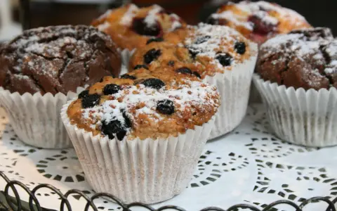 Fluffiga muffins med blåbär och choklad, pudrade med florsocker. Perfekt för ett enkelt muffins recept.