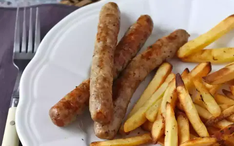 Saftig korv i airfryer med krispiga pommes frites på en vit tallrik. Enkel och god middag.