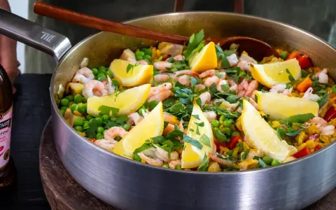 En härlig paella med räkor, ärtor och citronklyftor, perfekt för ett gott paella recept.