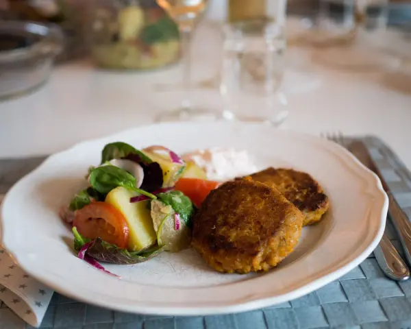 Två gyllenbruna biffar, troligen baserade på ett linser recept, serveras med en fräsch sallad och en klick sås.