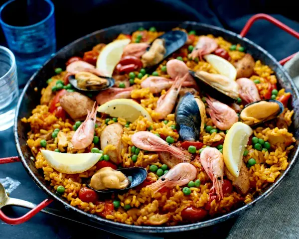 En stor paella med ris, räkor, musslor, gröna ärtor och citronklyftor. Perfekt vilket ris till paella som helst!