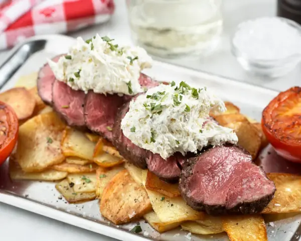 Saftig oxfilé Provencale med krämig topping, serverad med krispiga potatisskivor och grillade tomater. En festmåltid!