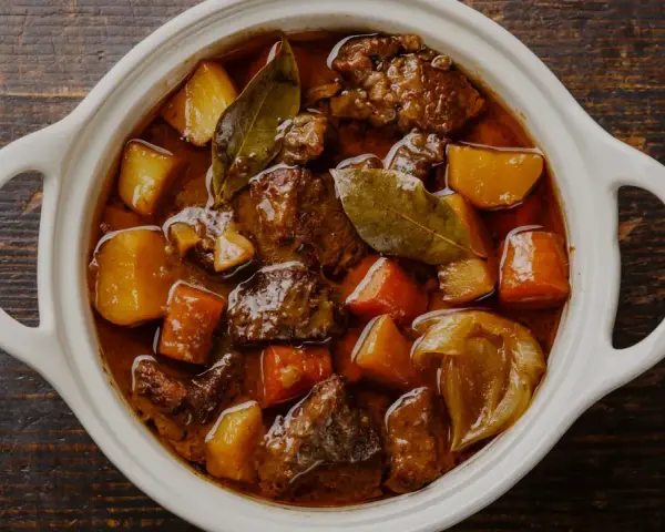 En vit gryta fylld med mustig boeuf bourguignon, med möra köttbitar, potatis och morötter. Perfekt vin till boeuf bourguignon.
