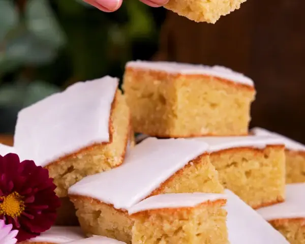 En härlig mazarinkaka i långpanna, skuren i bitar och dekorerad med blommor. En perfekt fika!