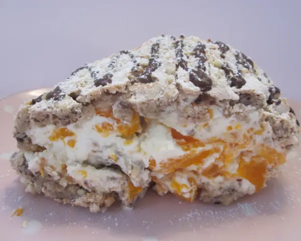 En bit av en Budapestrulle med aprikoser och grädde, toppad med choklad och florsocker. Ett härligt budapestrulle recept!