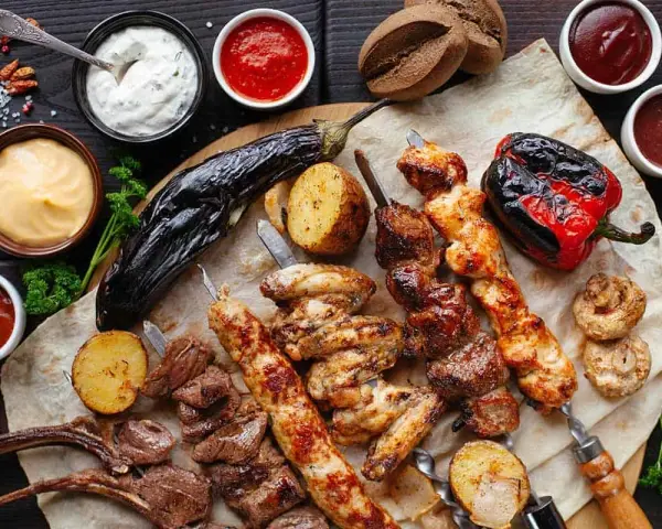 En härlig grilltallrik med köttspett, kycklingvingar, grönsaker och såser. Perfekt vin till tagliata.
