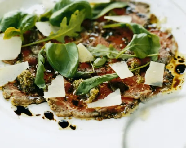 En läcker carpaccio med tunt skivad biff, parmesan, ruccola och pesto. Ett perfekt carpaccio recept för en fin middag.