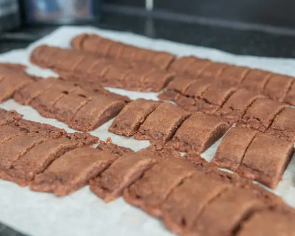 Chokladsnittar recept: Nybakade, mörka chokladkakor uppskurna i bitar på bakplåtspapper.