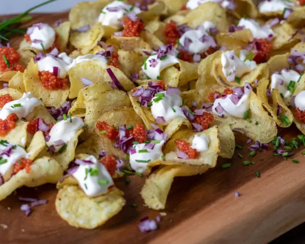 Krispiga chips med klickar av smetana, röd rom, finhackad rödlök och gräslök. En festlig förrätt!