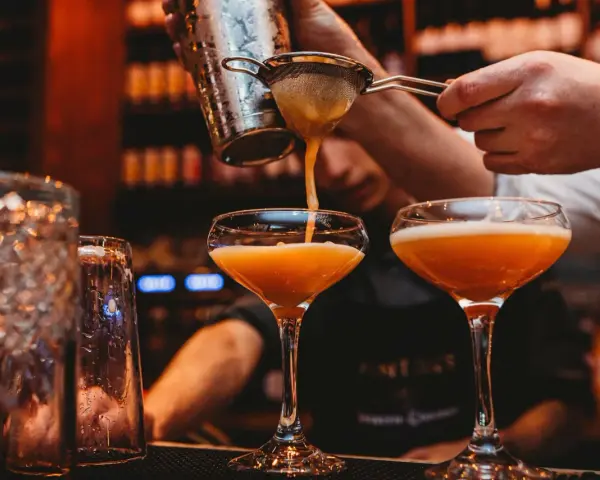 En bartender häller upp en Pornstar Martini i ett elegant glas.