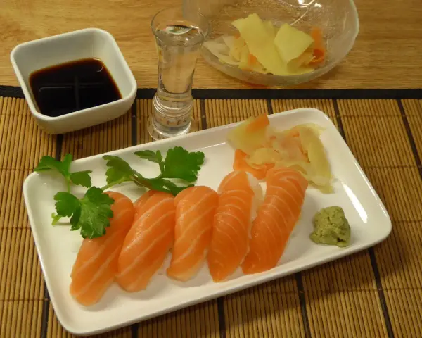 Njut av grillad lax sushi med wasabi, ingefära, sojasås och en shot sake.