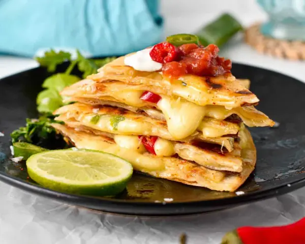 En stapel krispiga quesadillas med smält ost, jalapeños och salsa. Ett perfekt monterey jack ost alternativ för en smakrik måltid.