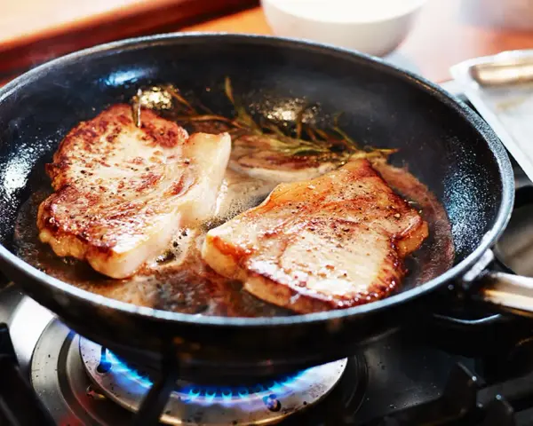 Två saftiga fläskkotletter steks i en panna med rosmarin. Ett perfekt karre recept för en god middag.