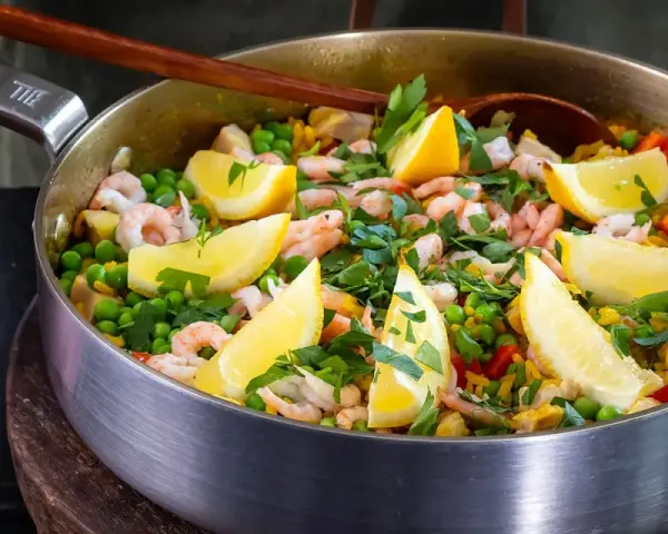 En härlig paella med räkor, ärtor och citronklyftor, perfekt för ett gott paella recept.