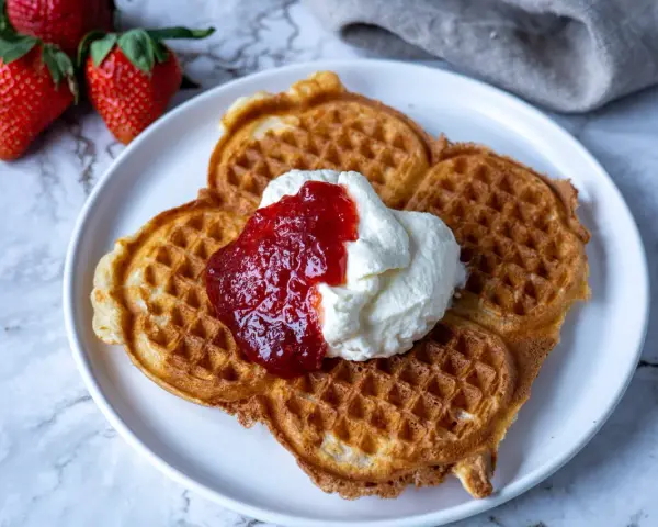 Gyllene belgiska våfflor med vispad grädde och jordgubbssylt. Ett perfekt recept för en lyxig frukost eller fika.