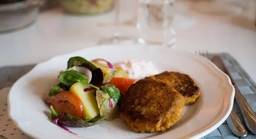 Två gyllenbruna biffar, troligen baserade på ett linser recept, serveras med en fräsch sallad och en klick sås.
