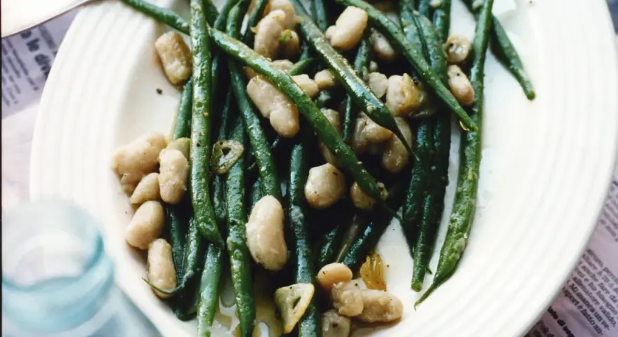 En tallrik med gröna haricots verts och vita bönor, lätt oljade och kryddade. En läcker och enkel rätt.
