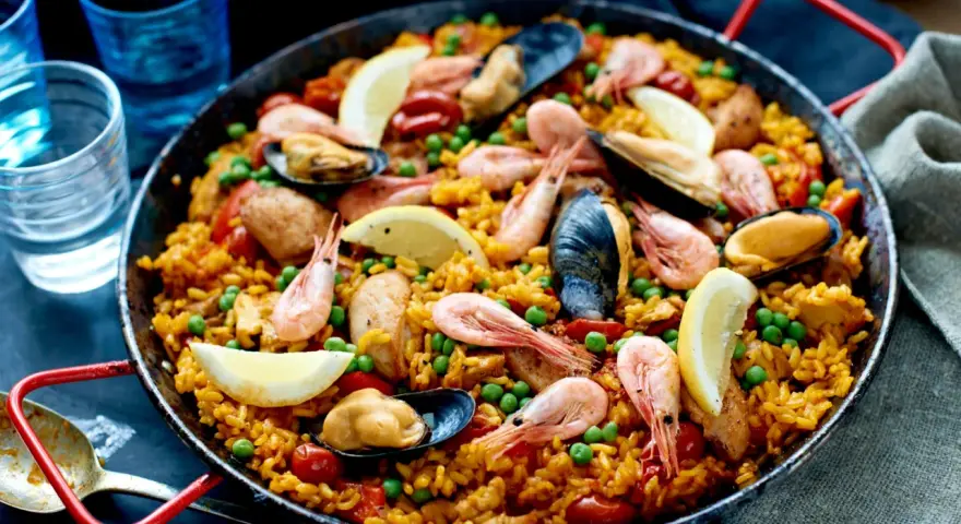 En stor paella med ris, räkor, musslor, gröna ärtor och citronklyftor. Perfekt vilket ris till paella som helst!
