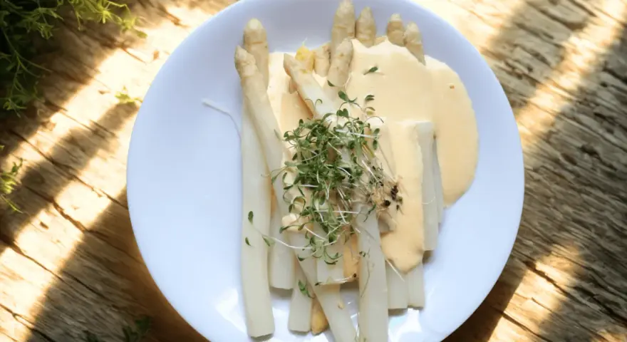Vit sparris serverad med en krämig sås och toppad med färska groddar. En delikatess som smakar sommar.