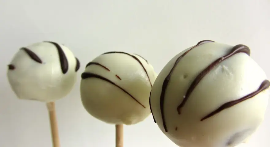 Tre vita cake pops med mörk chokladglasyr, perfekta för ett enkelt cake pops recept.