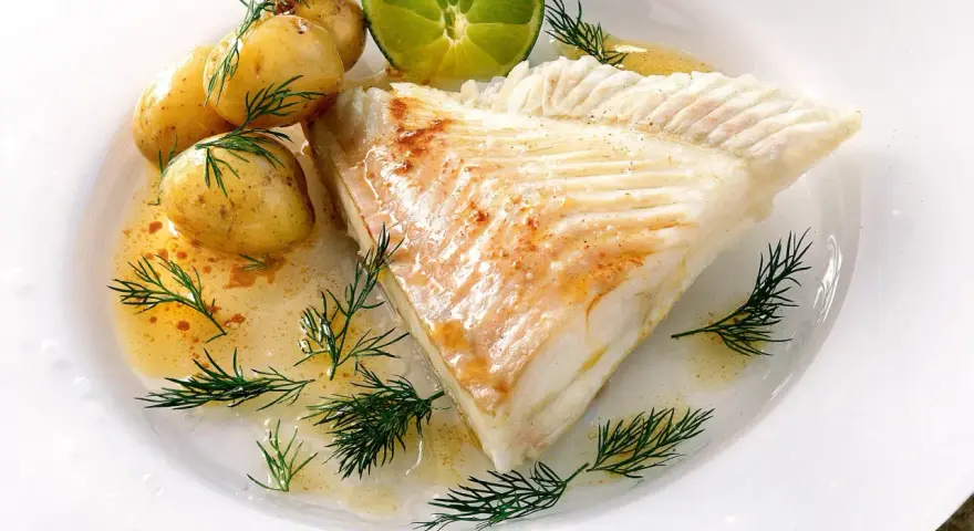 Piggvar i ugn serverad med småpotatis, dill och en limeklyfta. En delikat rätt som doftar hav.