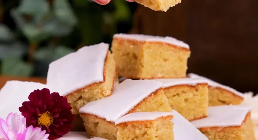 En härlig mazarinkaka i långpanna, skuren i bitar och dekorerad med blommor. En perfekt fika!