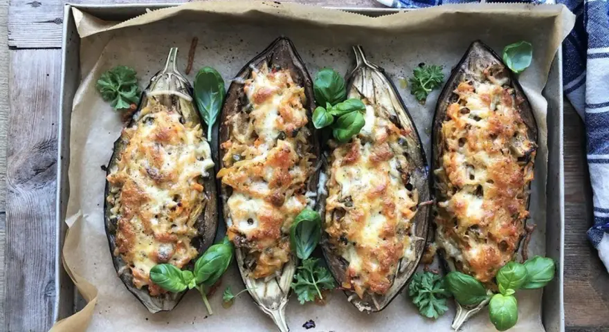 Fyra halverade auberginer fyllda med pasta och ost, ett läckert aubergine recept. Garnerade med färska örter.