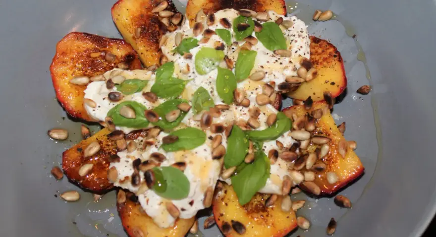 Grillad persika burrata med solrosfrön och basilika. En somrig rätt som smälter i munnen.