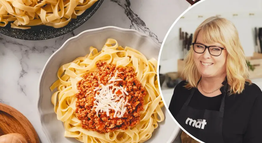 En kvinna med glasögon ler bredvid en skål med tagliatelle och köttfärssås. Perfekt för en snabb middag, den kokta pastan i kylen är redo att serveras.