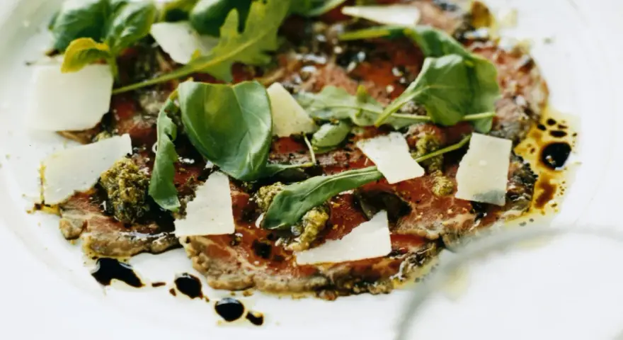 En läcker carpaccio med tunt skivad biff, parmesan, ruccola och pesto. Ett perfekt carpaccio recept för en fin middag.
