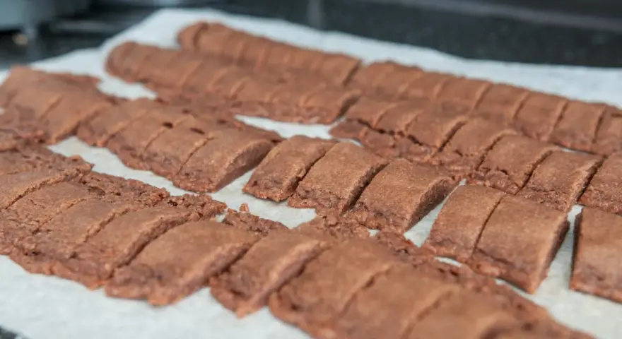 Chokladsnittar recept: Nybakade, mörka chokladkakor uppskurna i bitar på bakplåtspapper.