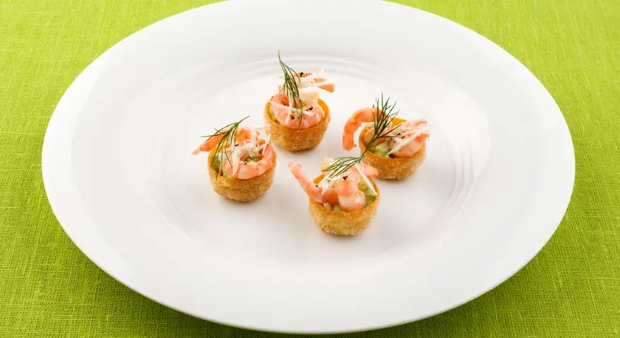Fyra små, krispiga tempura rolls med räkor och dill på en vit tallrik.