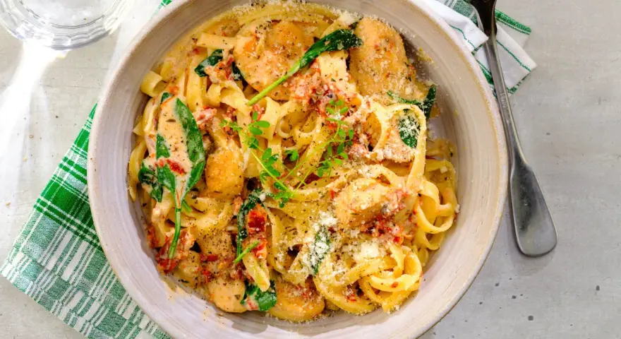 En krämig pastarätt med kyckling och soltorkade tomater, toppad med parmesan och färska örter.