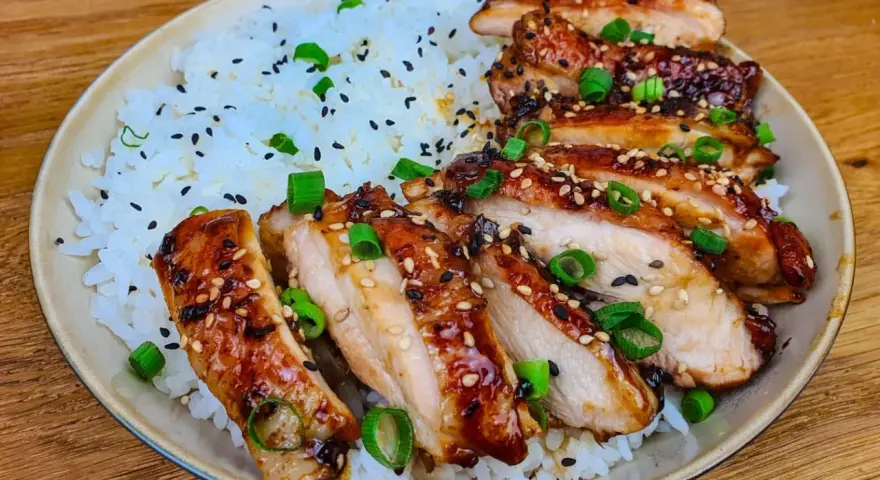 Skivad kyckling i gochujang marinad, serverad med ris och toppad med sesamfrön och salladslök. En härlig rätt som lockar smaklökarna.