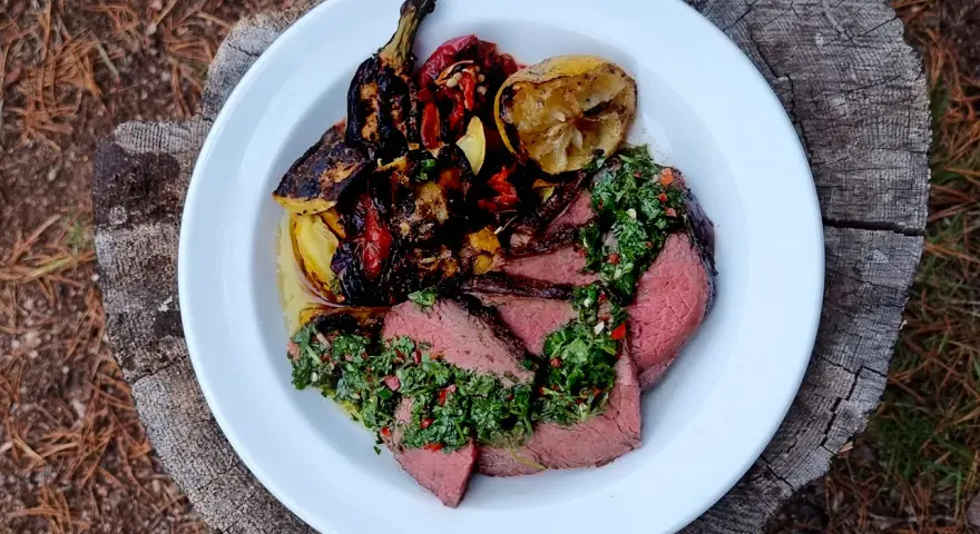 Skivat picanha på en tallrik med grillade grönsaker och citron. Perfekt för en somrig picanha grilla.