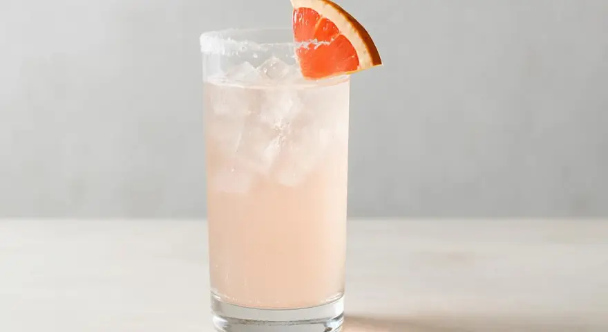En uppfriskande Paloma drink med is och en grapefruktskiva som garnering.